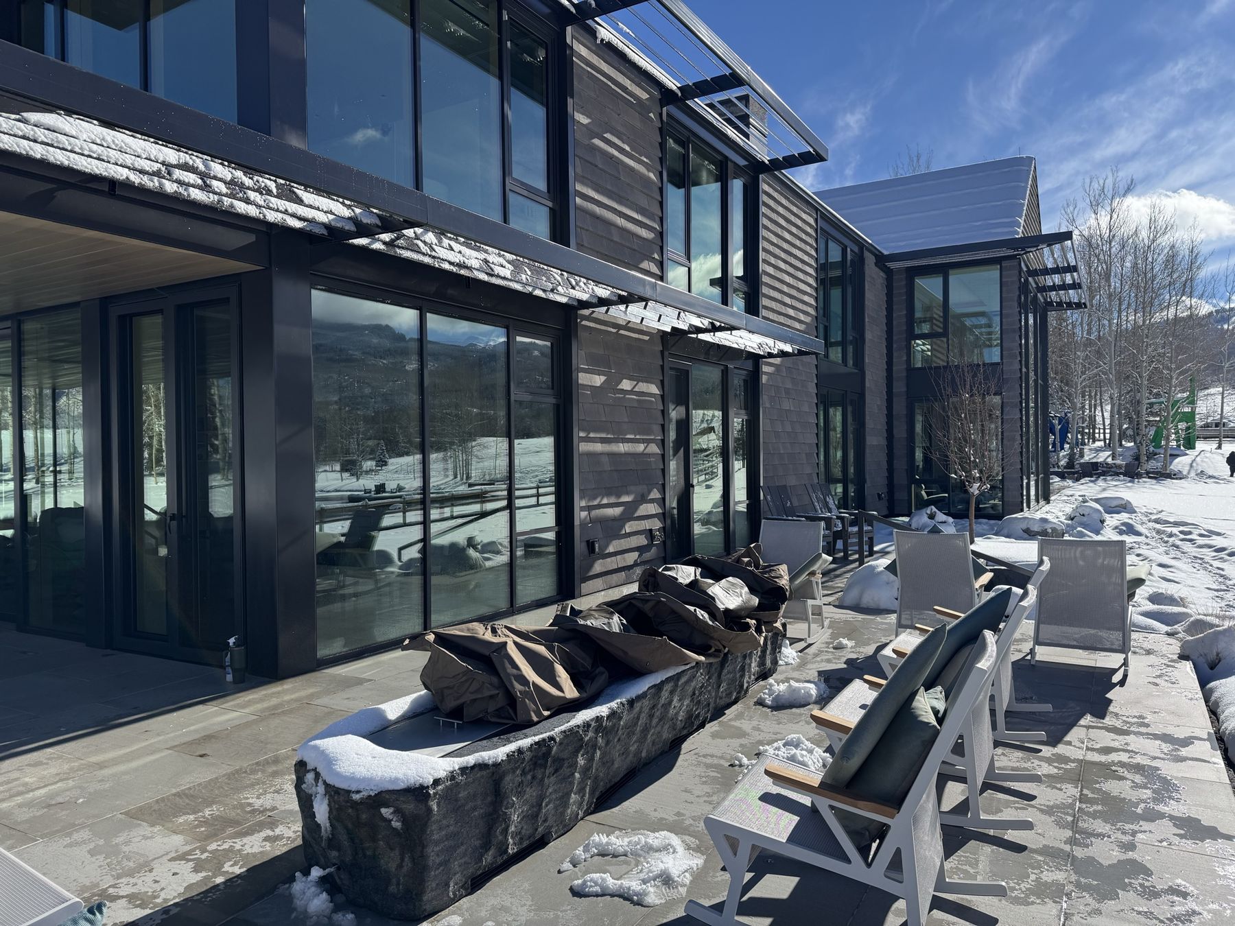 Finished mountain home with steel-framed windows, stone patio, and wood siding