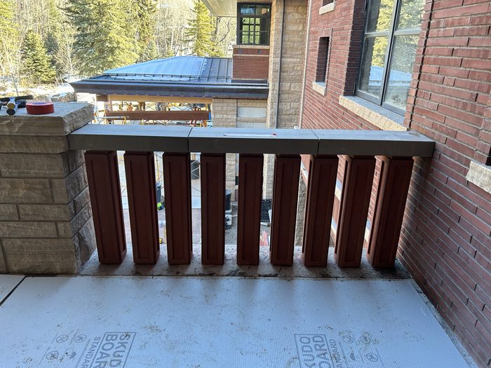 Completed railing run — terracotta balusters between a stone base and grey stone cap.