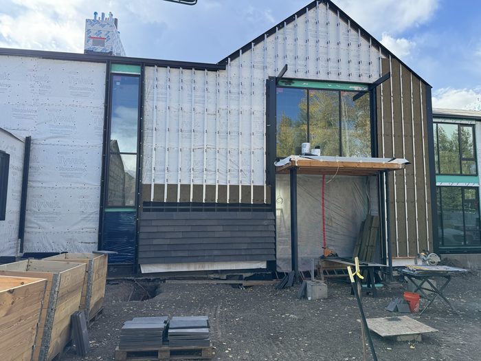 Weather barrier and vertical furring up, with the first courses of cladding started at the base.