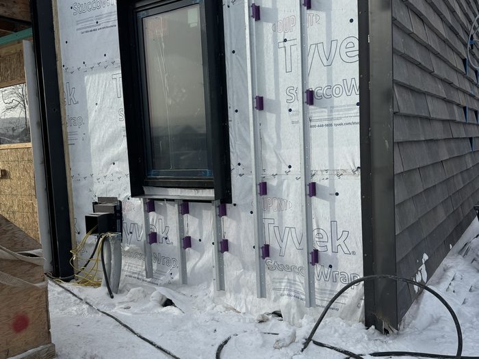 Furring channels and thermal clips set over the weather barrier; window flashed and ready to clad.