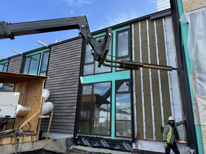 Rigid mineral wool insulation going in between the furring, crane staging material overhead.