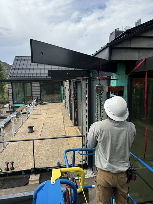 Installer on the terrace setting heavy horizontal steel beams.
