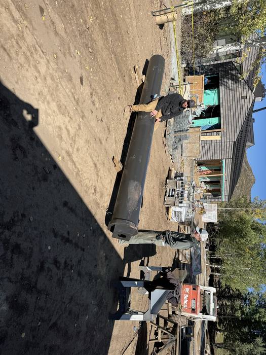 Large black steel beam section on the ground, awaiting install.