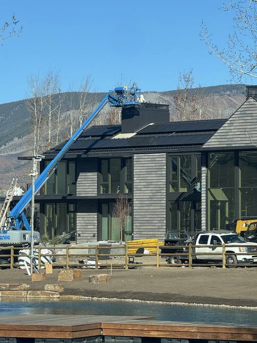 Multi-story glass wall with heavy steel mullions; boom lift on site.