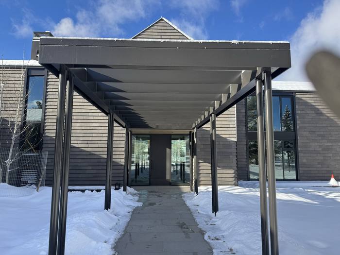 Entryway canopy — steel-framed, supported on dark beams.