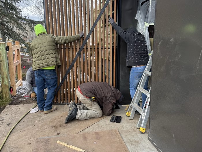 Crew maneuvering a finished panel into its track on the facade.