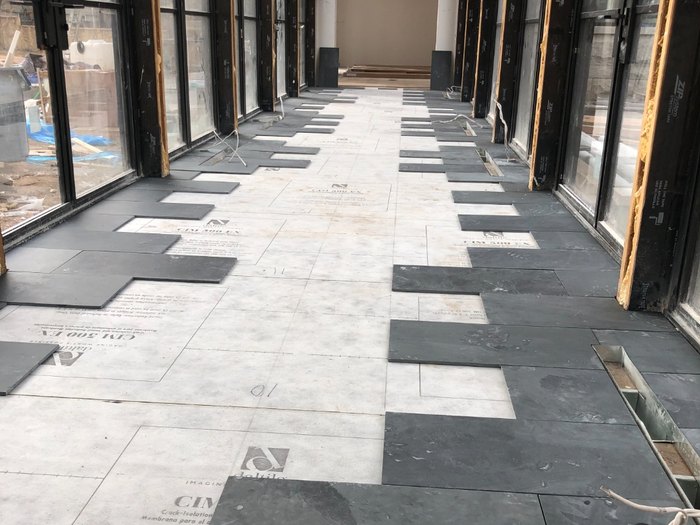 Slate laid out over Daltile crack-isolation membrane in the glass gallery, courses numbered before setting.