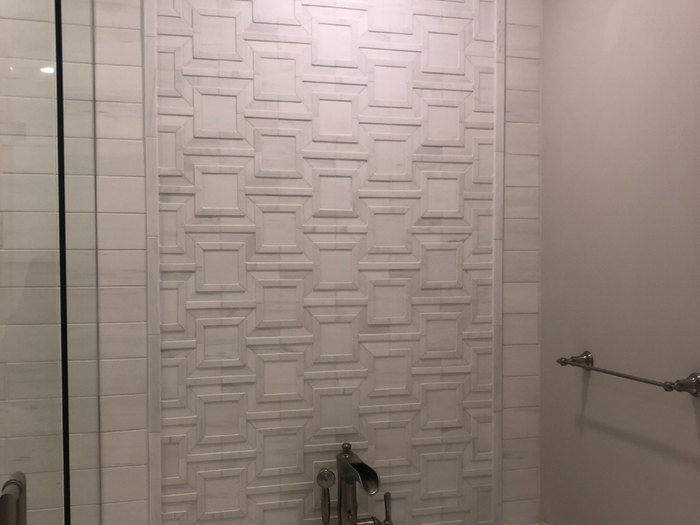 Dimensional carved marble panel framing the freestanding tub.
