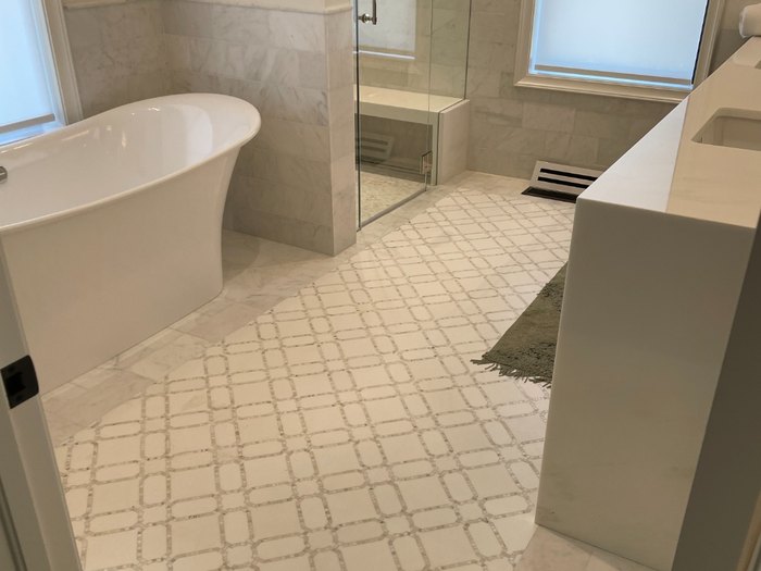 Marble bath with a mosaic field inlaid inside a slab border, tying the room together.