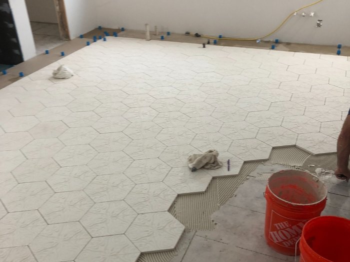 Patterned hex floor going in with leveling clips holding every joint flat.