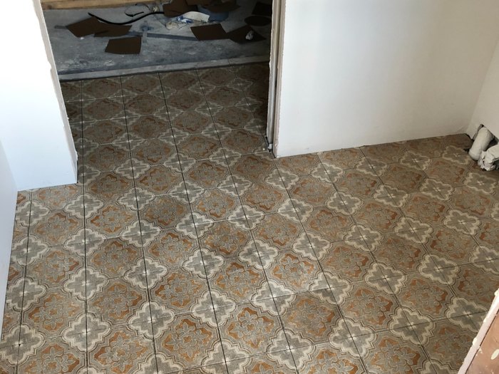 Encaustic-look patterned floor carried through the doorway on a continuous pattern line.