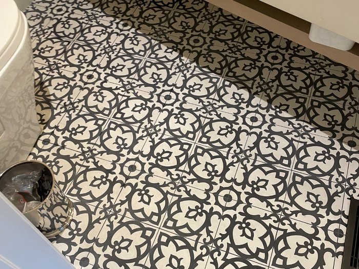 Black-and-white pattern floor in a powder bath, meeting slate at the threshold.