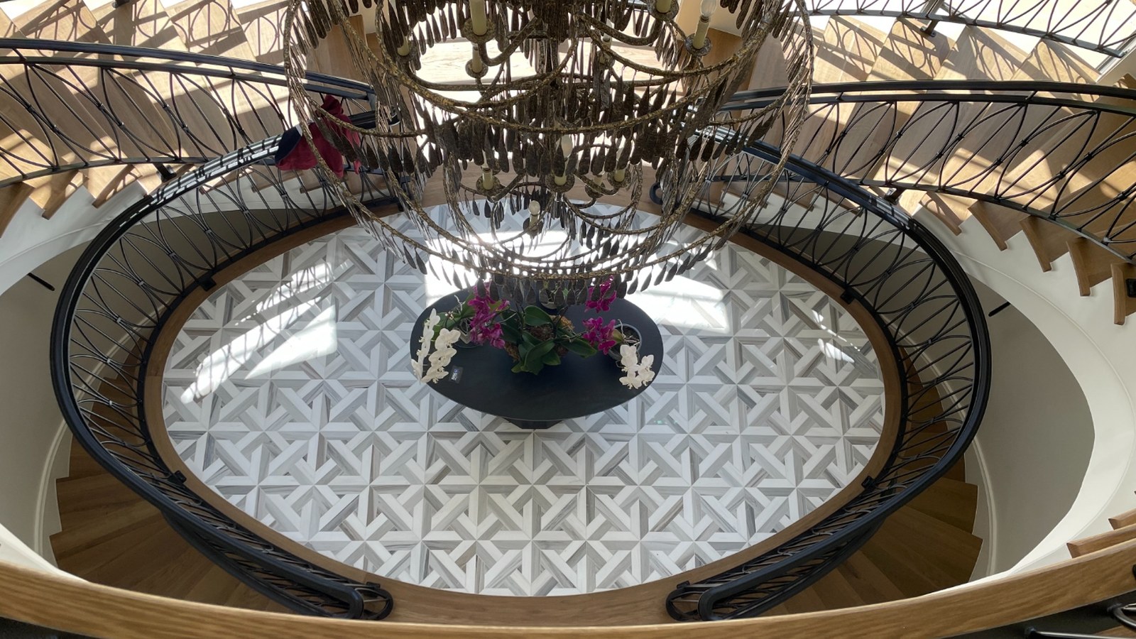 Marble pinwheel mosaic floor seen from above through the oval opening of a curved stair