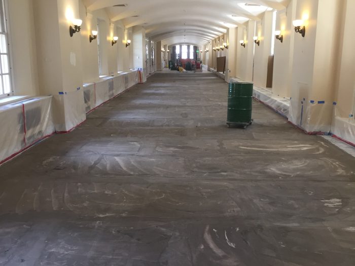 Corridor floor stripped down to raw stone, coating removed end to end.