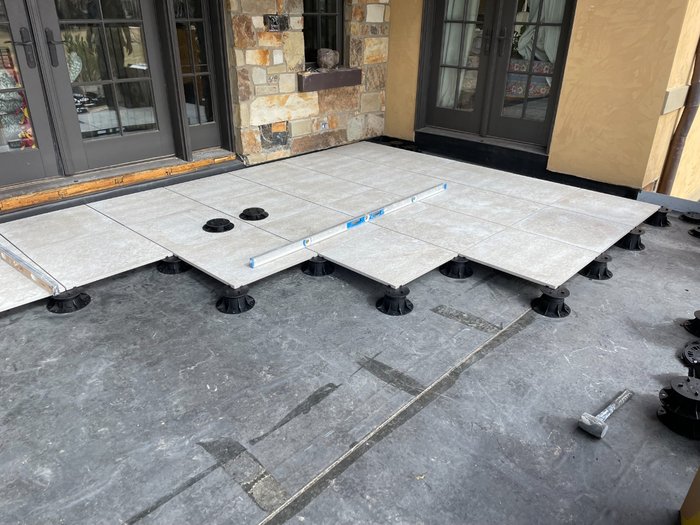 Pavers checked for level as the field advances — pedestal heights dialed in course by course.