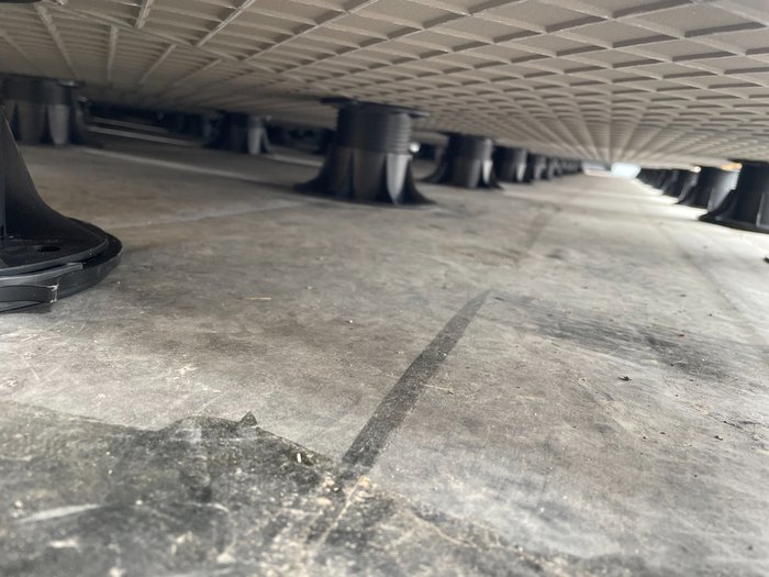 Under the deck — pedestals hold the pavers clear of the membrane so water runs to the drains.