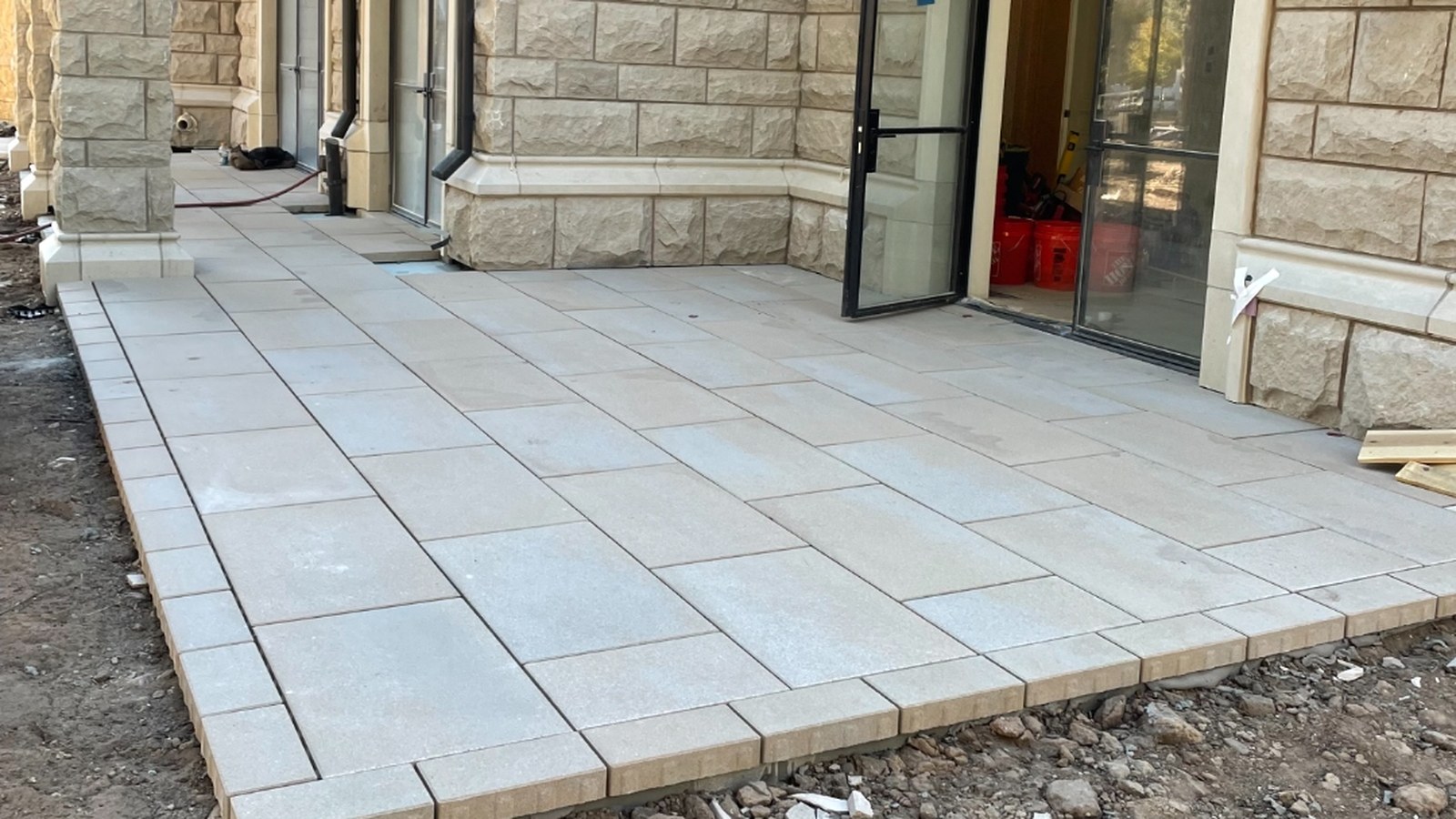 Finished paver terrace with a soldier-course border wrapping a stone-clad Denver residence
