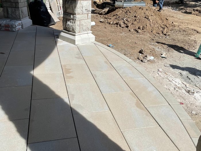 Curved walkway running out from the portico, base and drainage work still open alongside.