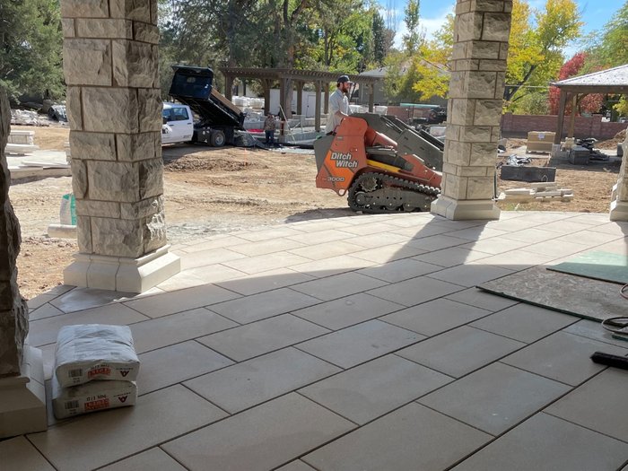 Set field under the portico, with base material and site work continuing past the columns.